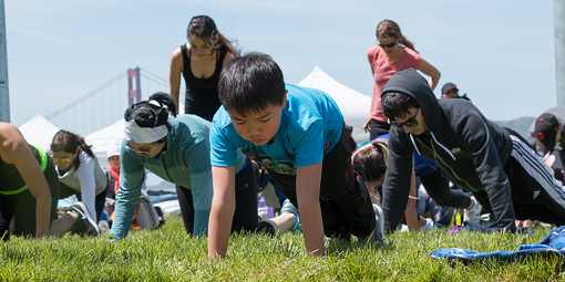 Children doing push ups outside. 